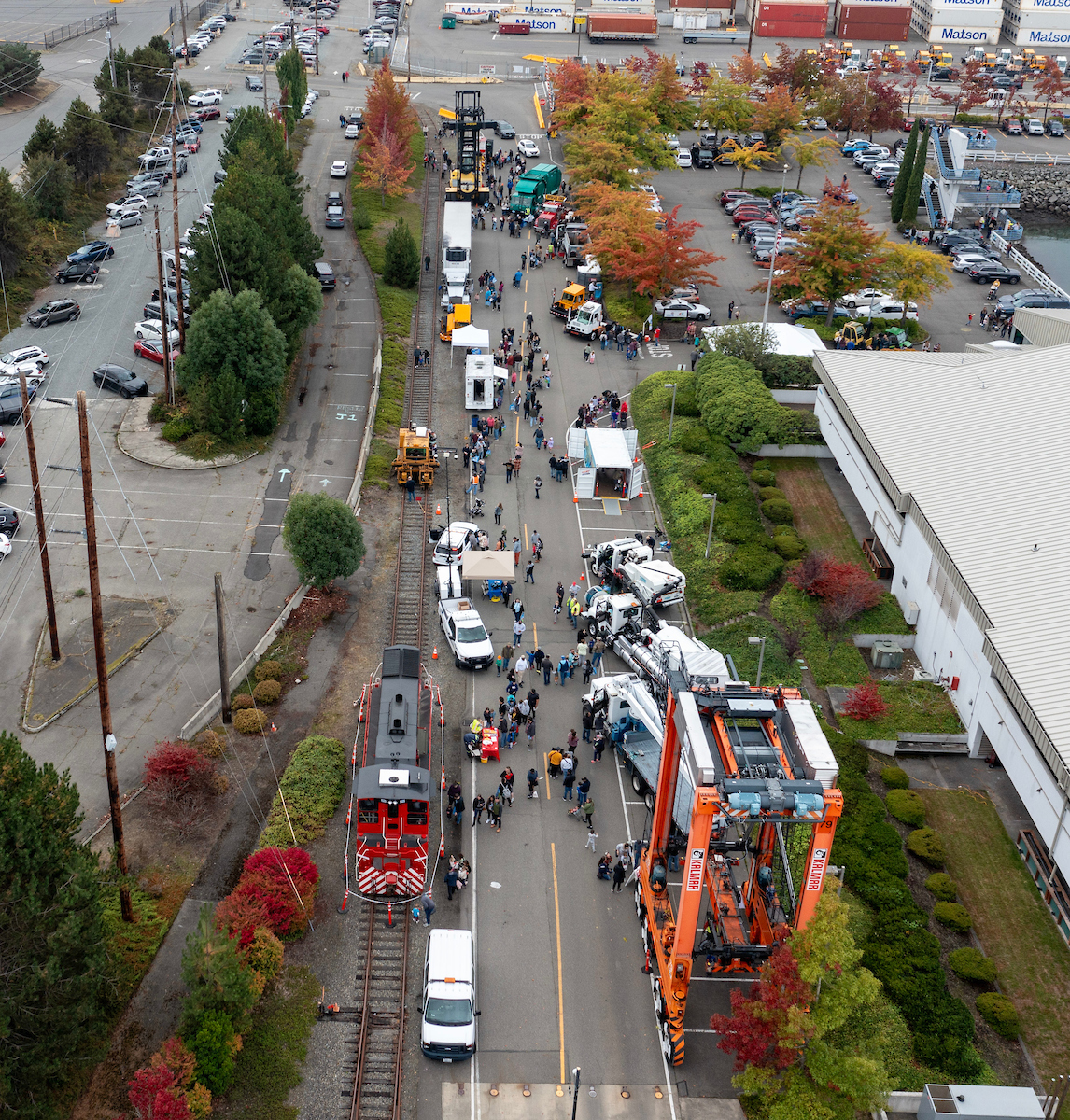 A drone shot of a street filled with cranes and construction vehicles with people moving between them.