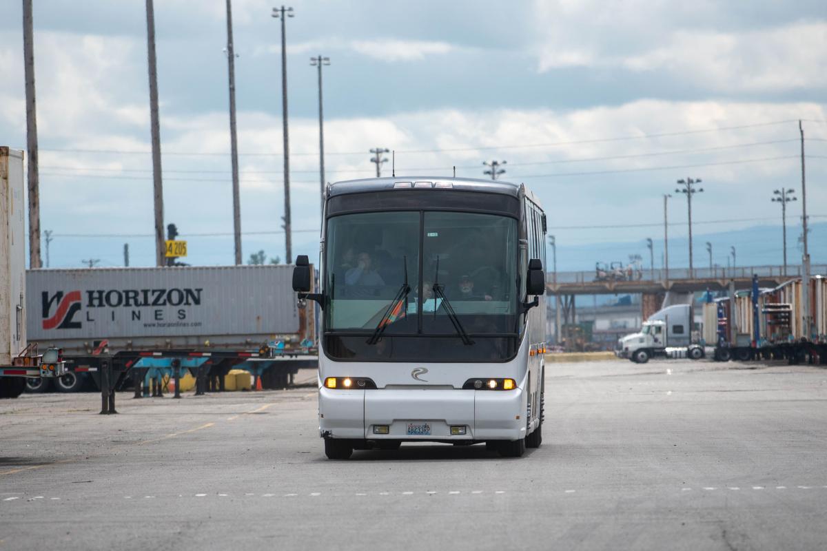 The front of a white and black bus in a parking lot. 